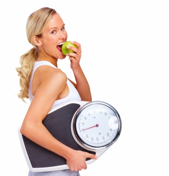 Woman eating apple holding scale